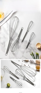 Close-up of stainless steel spring whisks with spiral handles and hanging loops