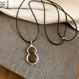 New Chinese style leather gourd pendant necklace with a black cord on a grey canvas