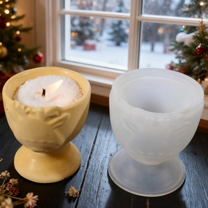 Silicone mold for embossed elk candle jar beside a finished yellow decorative wax cup