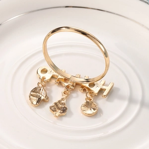 Golden Christmas napkin ring with tree, glove and gift pendants on a white ceramic plate