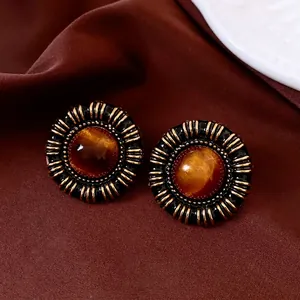 Vintage round resin earrings with black gold pleated texture on deep red silk background