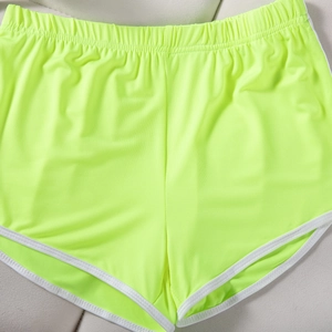 Flat lay of neon green sports shorts with elastic waist and white contrast piping detail