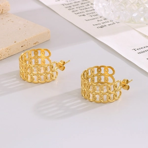 Detailed close-up of hollow gold-plated chain link earrings on a minimalist stone base