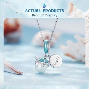 Macro view of sea turtle pendant with blue enamel, white pearl, and Enjoy life tag