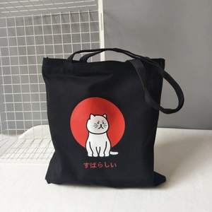 Detail of a black canvas tote bag featuring a white cat graphic and Japanese text