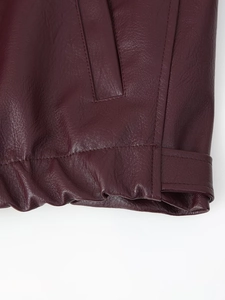 Detailed macro shot of dark red leather jacket with precise stitching and elastic hem