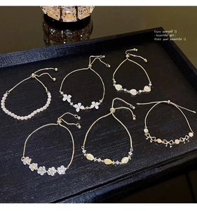 Detailed view of six gold-tone adjustable slider bracelets with floral and opal pendants
