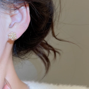 Close-up of elegant flower cluster pearl earring with gold metal accents on model