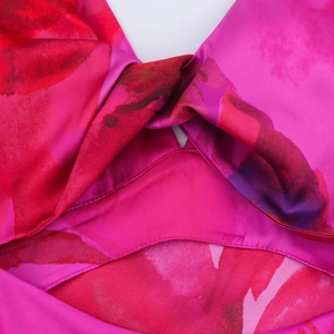 Détail du design torsadé de cette robe licou à imprimé floral de couleur fuchsia