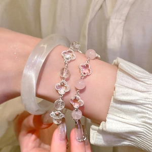 Detail of beaded clover bracelets and white translucent bangle on a feminine wrist