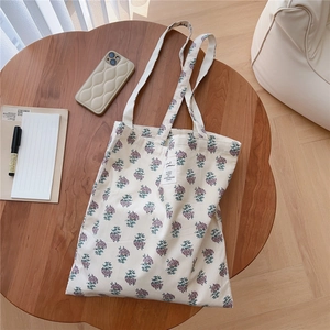 Close-up of vintage floral canvas tote bag with purple flower print on a wooden table