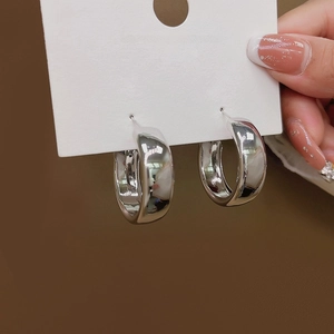 Minimalist glossy silver chunky hoop earrings held on a white jewelry card for women