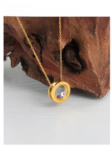 Detailed macro view of a gold Roman numeral pendant necklace with colorful inlay