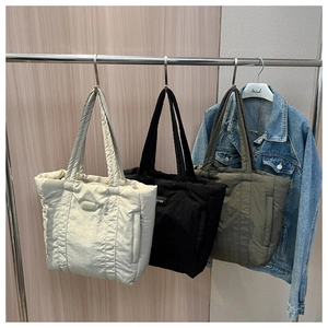 Hanging display of padded nylon tote bags in beige, black, and olive green colors