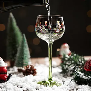 Creative hand-painted wine glass with folk figures and a festive green stem in winter setting