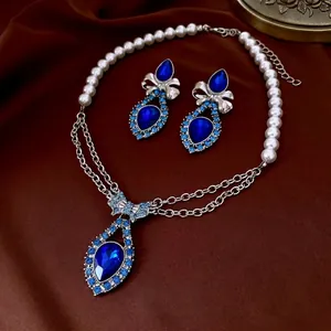 Blue waterdrop crystal jewelry set with pearl necklace and matching earrings on silk