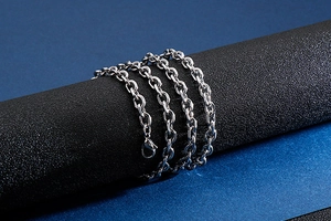 Detailed view of silver stainless steel cable chain necklace on a dark display stand