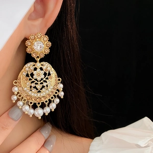 Detail of vintage style golden drop earrings with pearls and crystals on a model