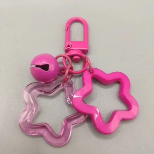 Pink acrylic hollow star keychain with matching bell and chain on grey background