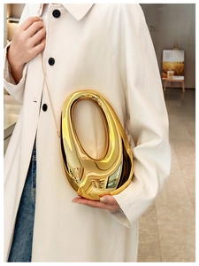Close-up of a gold acrylic evening clutch featuring a unique hollow circular handle design