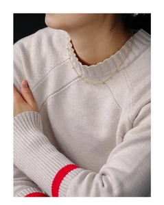 Detail shot of golden zircon beaded necklace worn on a cream sweater for styling