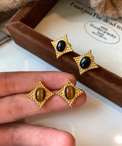 Vue détaillée de boucles d'oreilles vintage en or avec pierres œil de tigre et étoiles