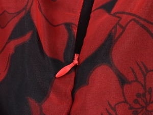Détail d'une fermeture éclair invisible rouge sur tissu d'organza floral rouge et noir