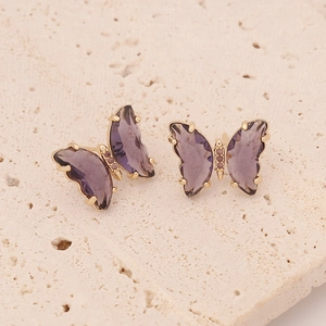 Macro shot of purple butterfly earrings with zircon stones and golden metal claws