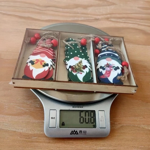 Three Christmas wooden gnomes in a box being weighed on a scale showing 60.8g
