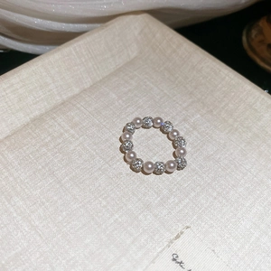 Detail of beaded ring with white pearls and sparkling rhinestone sphere on tray