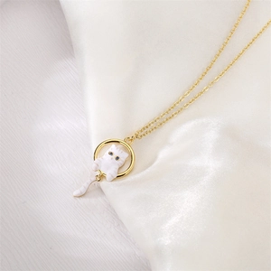 Detailed view of cat pendant necklace with blue eyes on gold ring and silk background