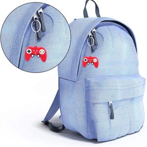 Red silicone game controller keychain with silver metal ring on a blue denim backpack