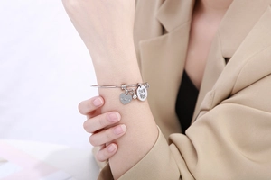 Detailweergave van de zilveren hartbedeltjes met Love-gravure op de roestvrijstalen armband
