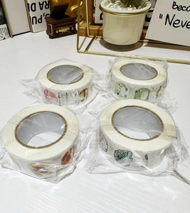 Close-up of four rolls of cartoon reward stickers with English phrases for scrapbooking
