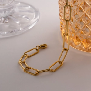 Détail macro du bracelet à maillons trombone dorés avec fermoir mousqueton et fini brillant