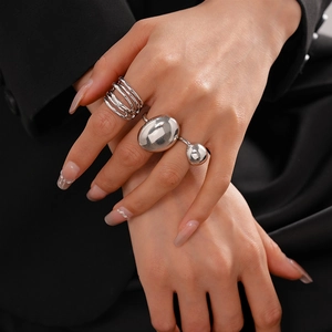 Detailed view of silver multi-layer intertwined ring and asymmetric ball ring on hand