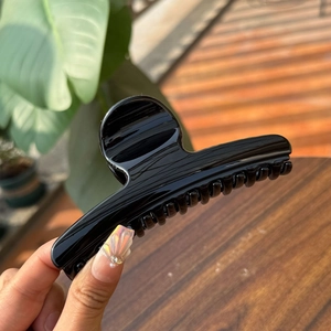 Detailed close-up of a glossy black hair claw clip showing smooth resin finish and teeth