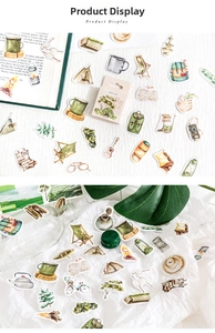 Macro detail of hand-drawn camping stickers featuring tents and forest motifs in a gift box