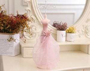 Detailed pink lace mannequin jewelry stand with white metal hooks on a vanity desk