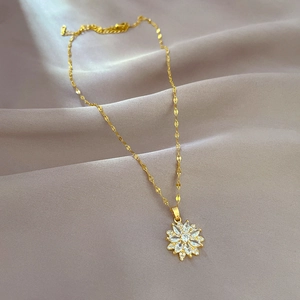 Macro detail of gold flower pendant with sparkling crystals on soft beige fabric