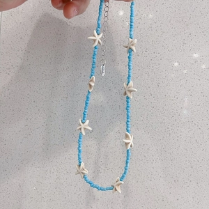 Detail showing blue beads, white starfish charms, and the Hand Made tag on this necklace
