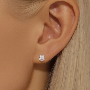 Macro detail of oval-cut crystal stud earring with silver claw setting on ear