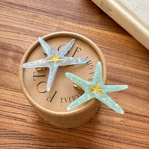 Detail of starfish hair clips in pearly white and mint green with golden accents
