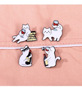 Detail of four cute white cat enamel pins with wine theme on pink fabric background
