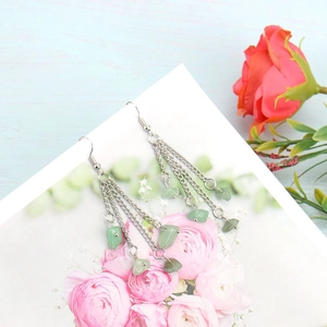 Detail of silver long tassel earrings with light green natural crystal stone beads