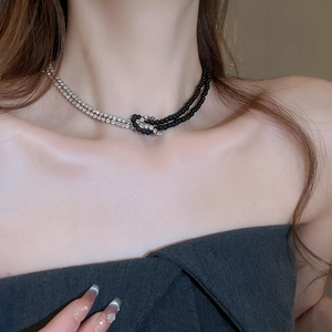 Dettaglio della collana Y2K con cristalli argento asimmetrici e catena di perle nere