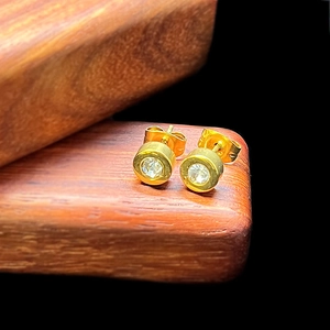 Macro shot of gold-plated mini screw back stud earrings with clear round cubic zirconia