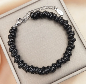 Detail of black twisted bead bracelet with stainless steel lobster clasp and logo tag