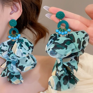 Close-up of green leopard print fabric tassel earrings with beaded floral texture