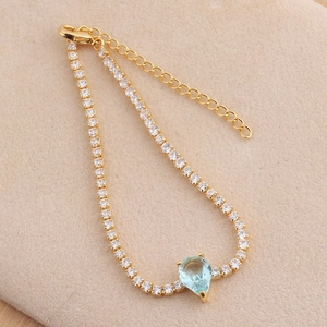 Detail of gold tennis bracelet with teardrop blue stone and micro-pave white zircons